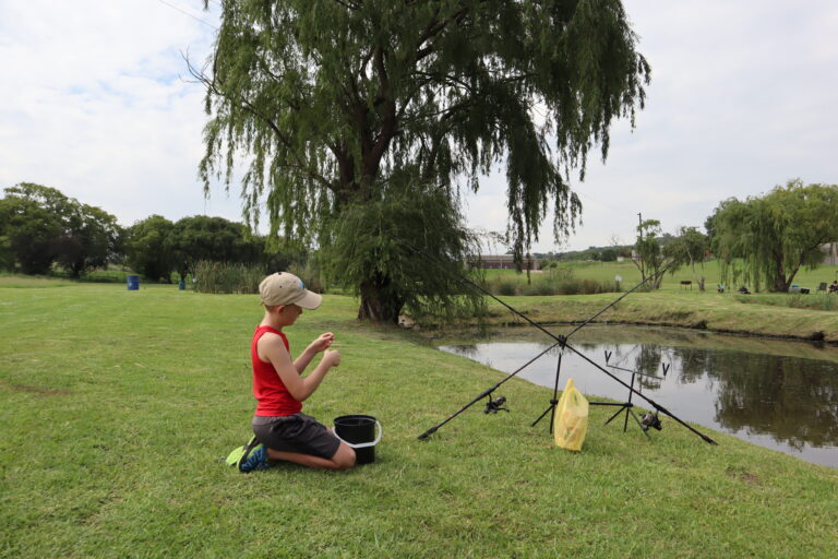 Willow Waters Son preparing his carp rod on the green banks of the dam.