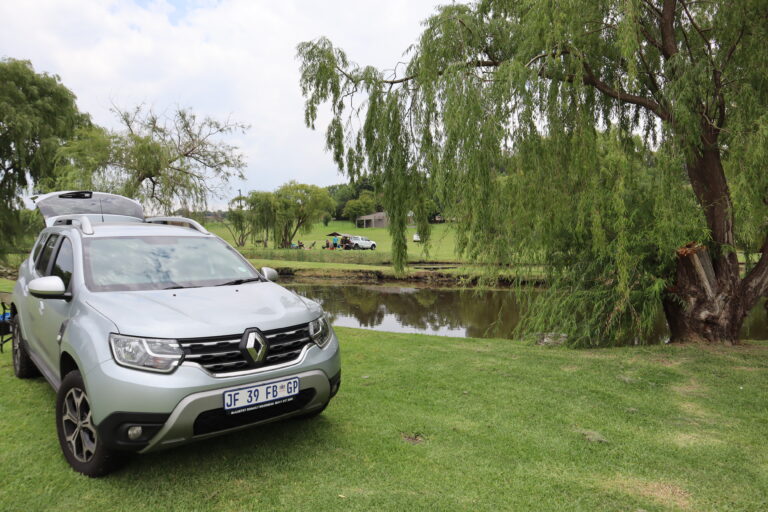 Willow Waters Renault Duster next to the dam on green grass with a Weeping WIllow